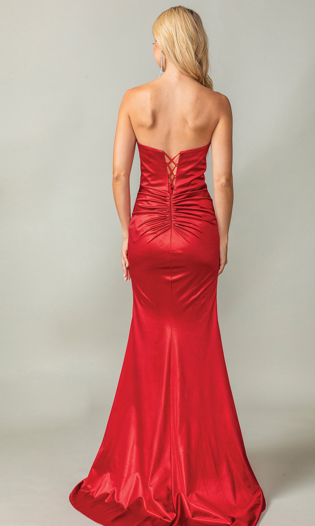 A woman, seen from behind against a plain backdrop, wears the Dancing Queen 4407—a floor-length, strapless prom dress with a sweetheart neckline and lace-up back.
